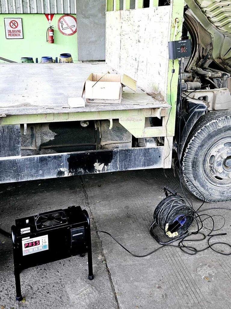 Proses pengambilan sampel uji emisi kendaraan logistik oleh teknisi AdhikariLab